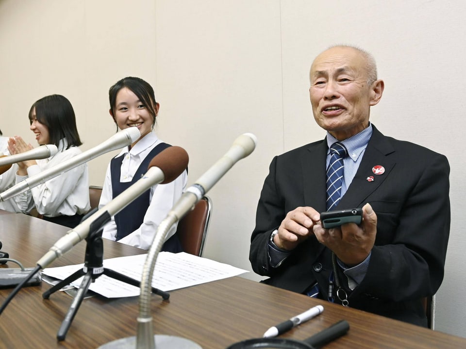 Tomoyuki Minomaki und zwei Frauen bei einer Pressekonferenz