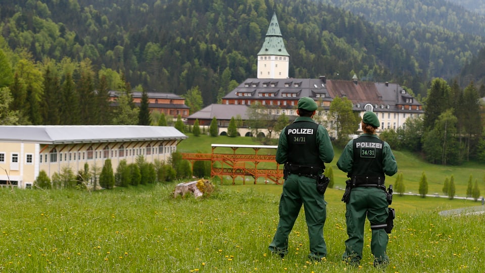 Polizisten blicken auf das Schloss Elmau.