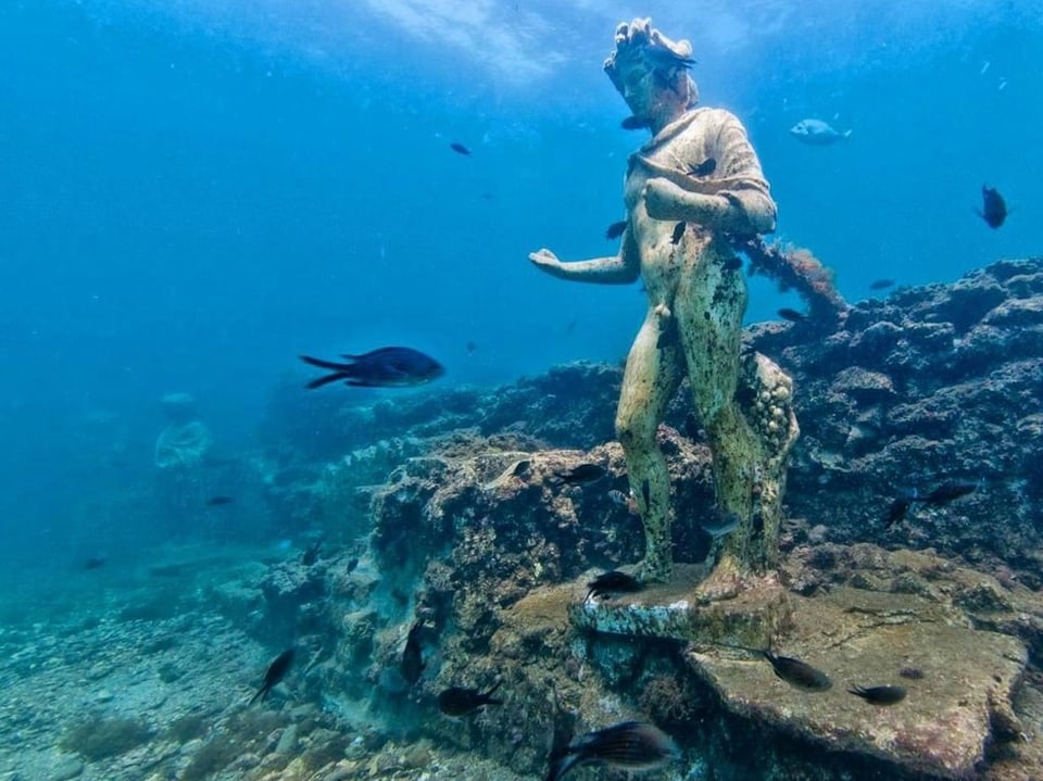 Unterwasserstatue mit Fischen im Meer.