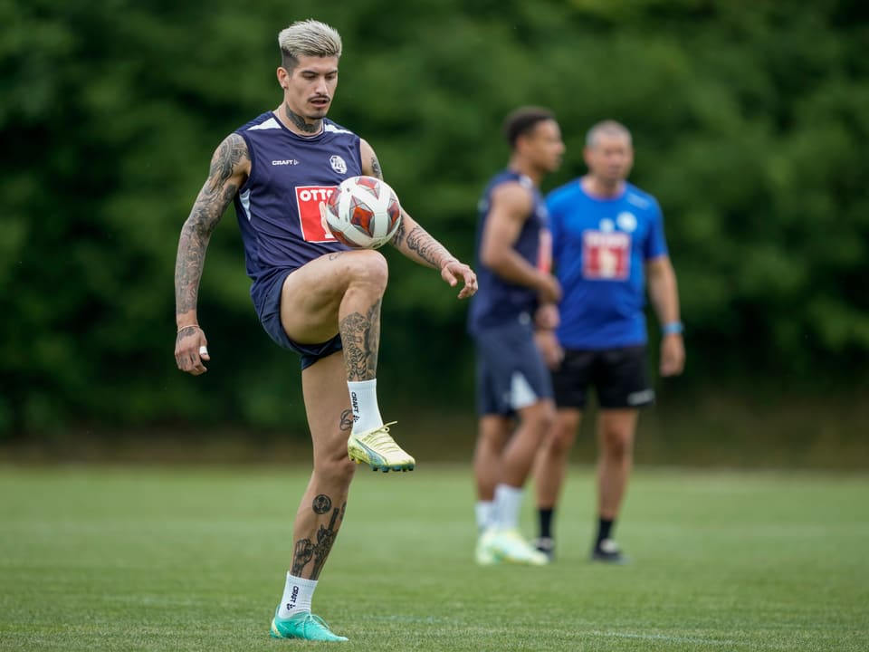 Fussballspieler jongliert Ball im Training auf Rasenplatz.