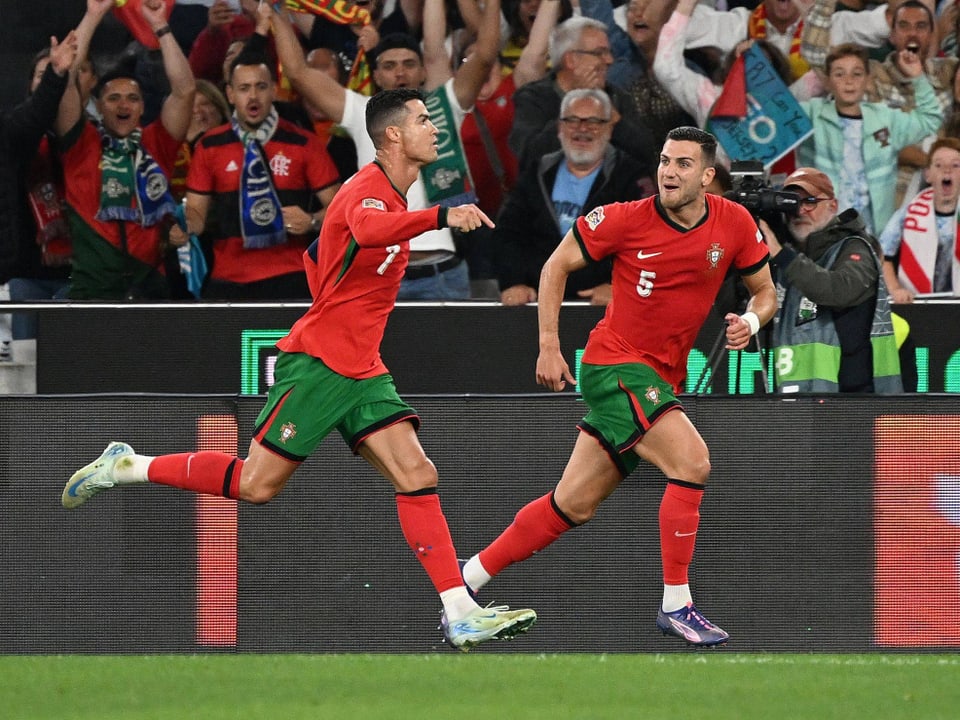 Zwei portugiesische Fussballspieler feiern ein Tor vor jubelnden Fans.