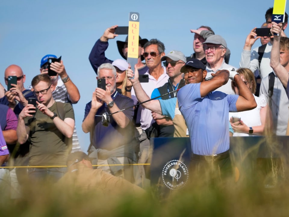 Golfer schlägt Ball vor Zuschauern.