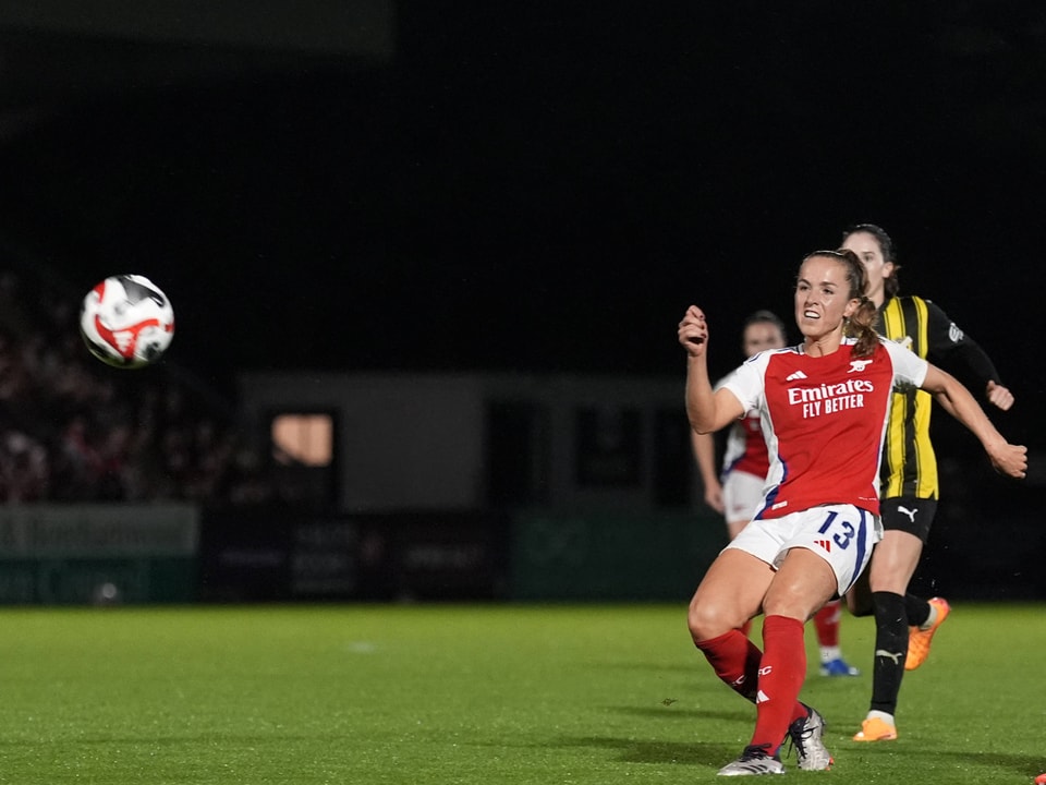 Fussballspielerin in rotem Trikot verfolgt den Ball.