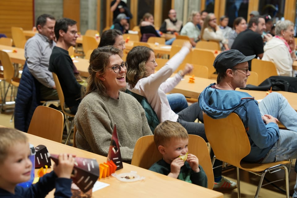 Menschen in einer Halle auf Stühlen sitzend, Feier oder Versammlung.