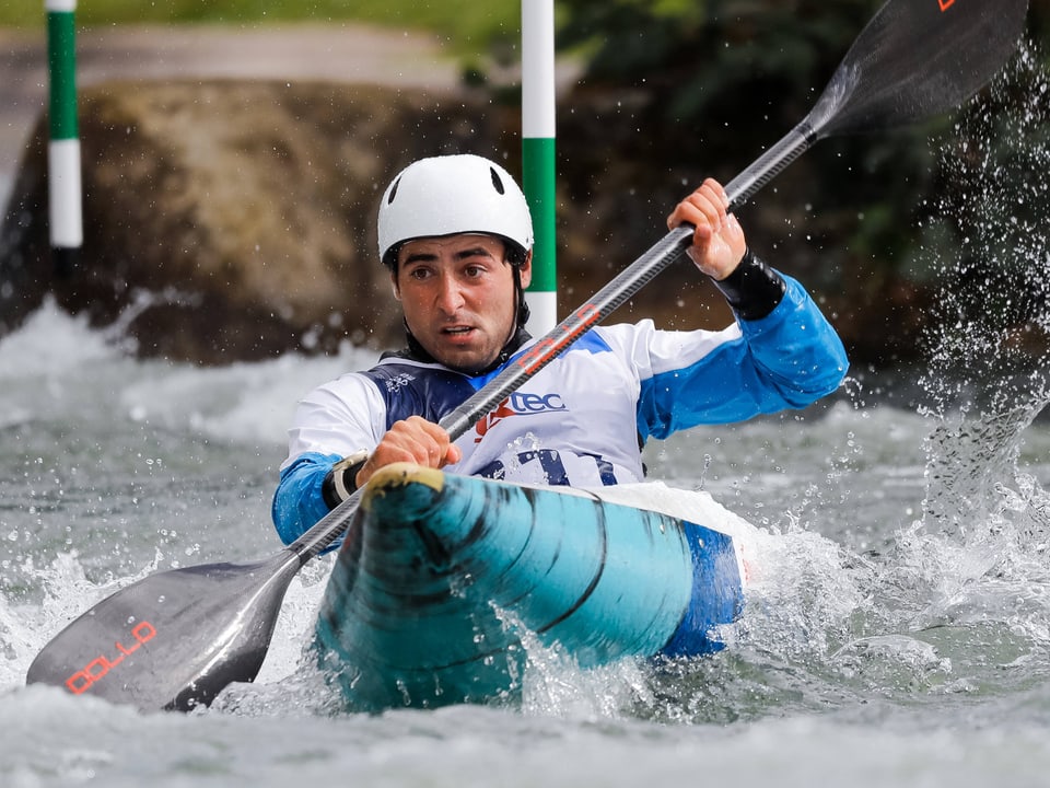 Kanufahrer mit Helm und Paddel im Wildwasser.