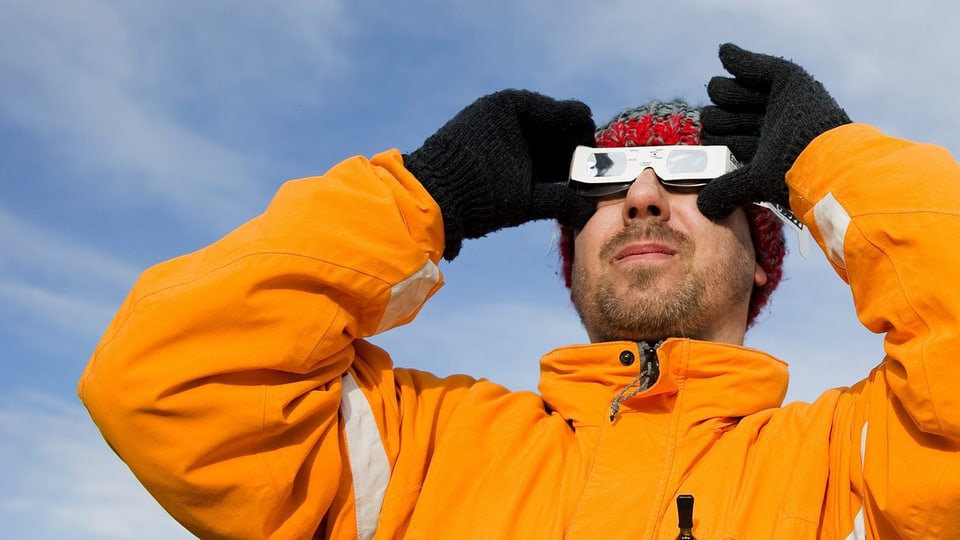 Ein Mann beobachtet durch eine Brille die Sonnenfinsternis