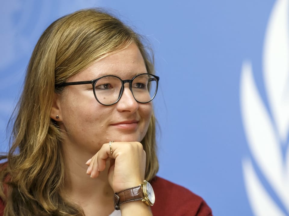 Frau mit Brille vor blauem Hintergrund.