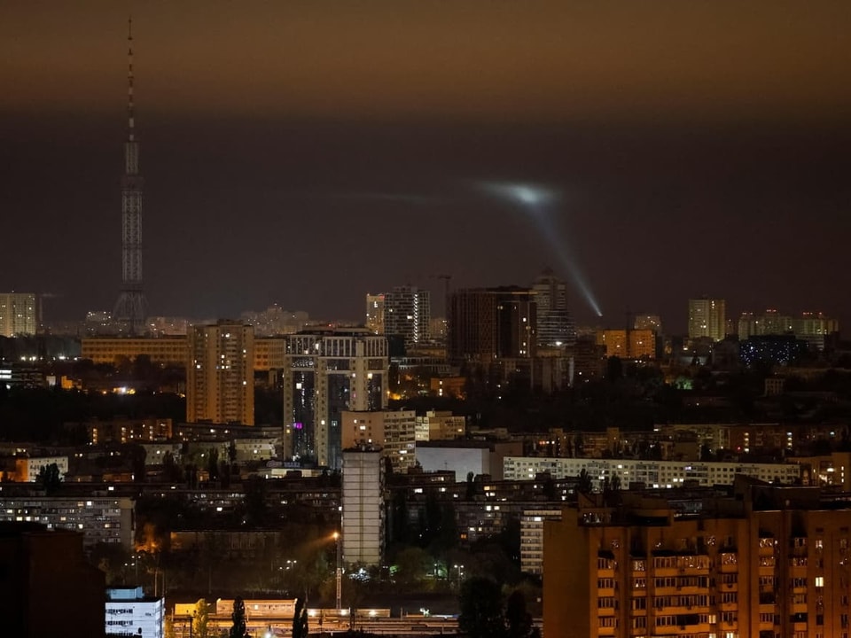 Nachtansicht einer Stadt mit beleuchtetem Funkturm und Himmel.