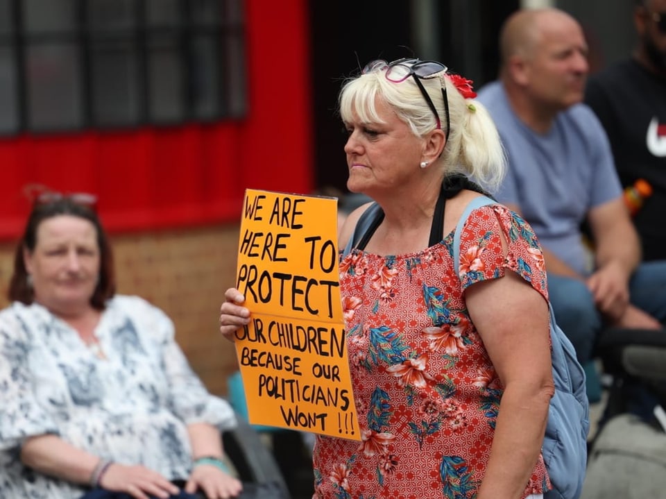 Eine Frau hält ein Plakat: "Wir sind hier, um unsere Kinder zu beschützen, weil es die Politiker nicht machen..