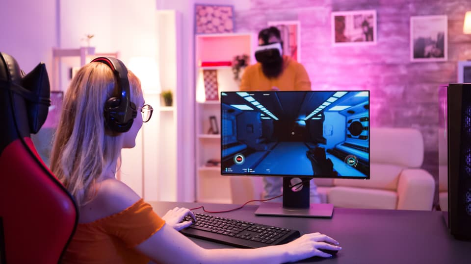 Frau sitzt am Computer und spielt Videospiel.