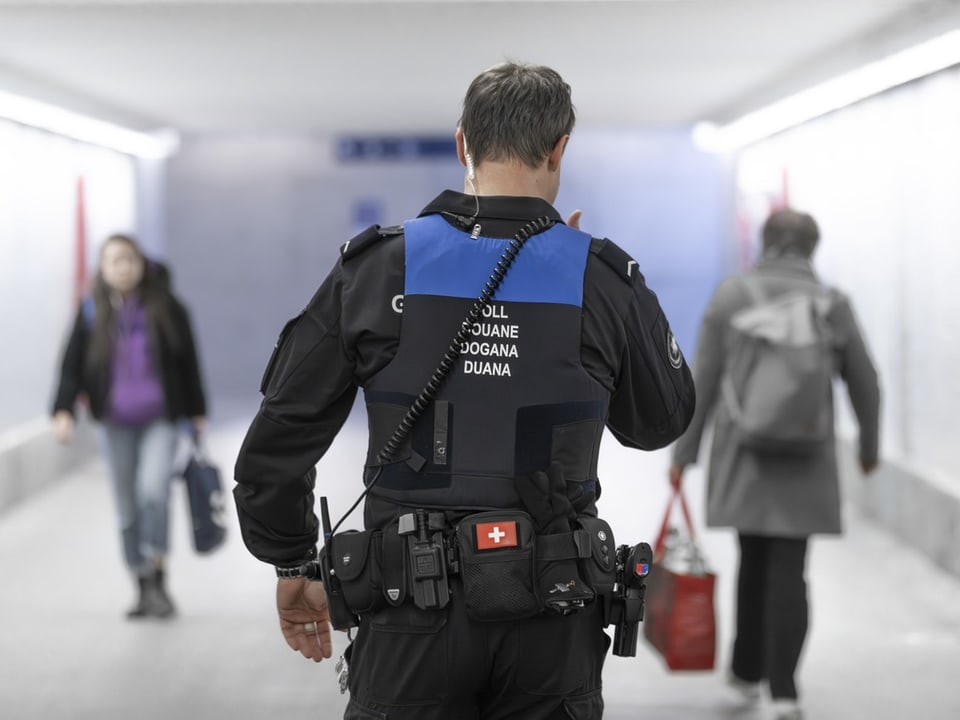 Zollbeamter von hinten im Tunnel mit Passanten.