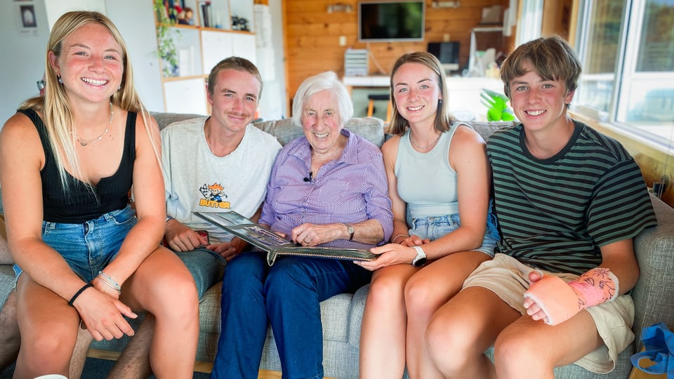 Hanni Padrutt und 4 Enkel und Enkelinnen sitzen auf dem Sofa und lächeln in die Kamera