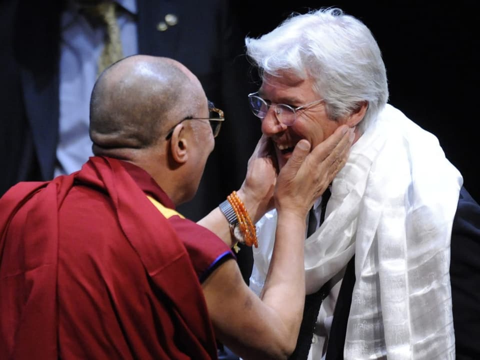 Der Dalai Lama berührt Richard Gere im Gesicht