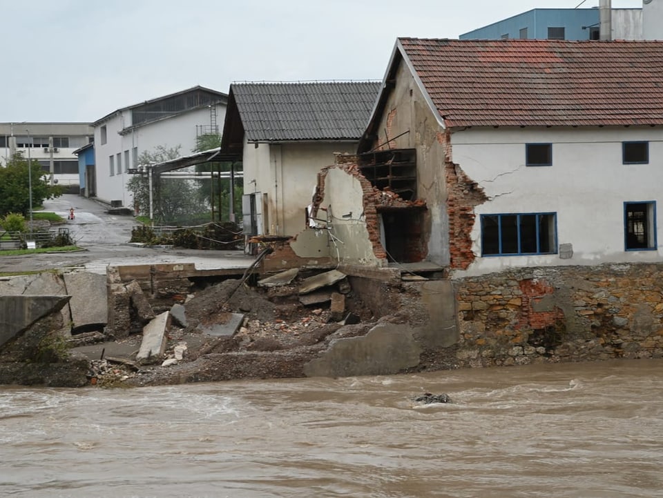 Zerstörtes Haus, daneben Wassermassen.