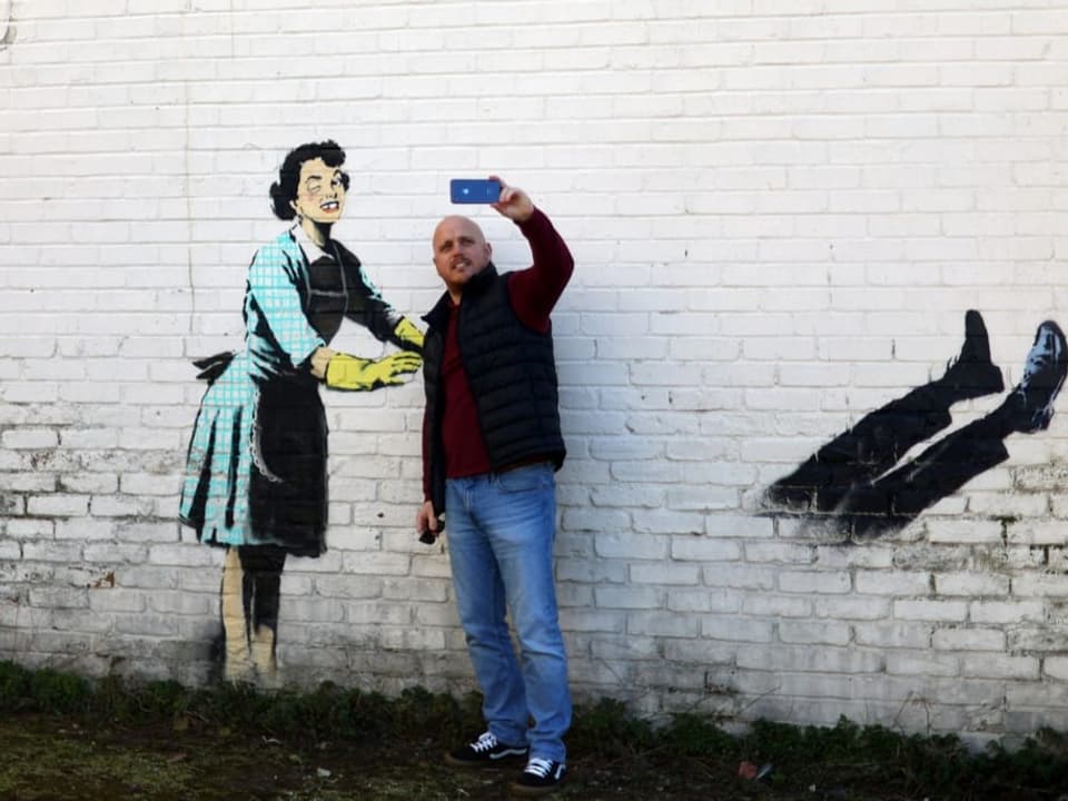 Mann macht Selfie vor Graffiti