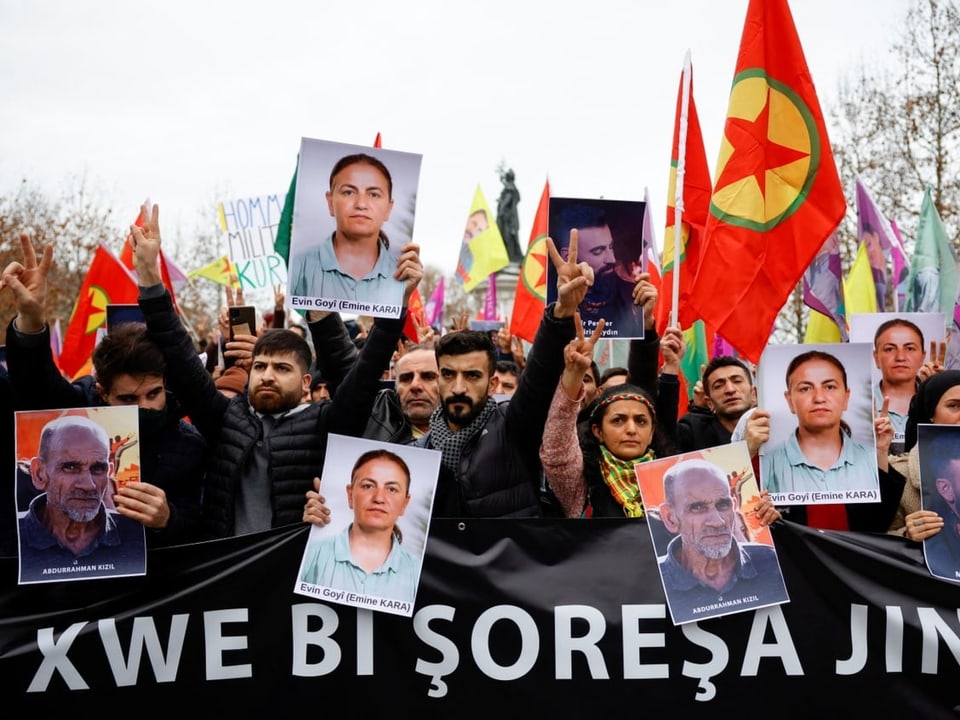 Menschen protestieren mit kurdischen Flaggen und Bildern von Getöteten.