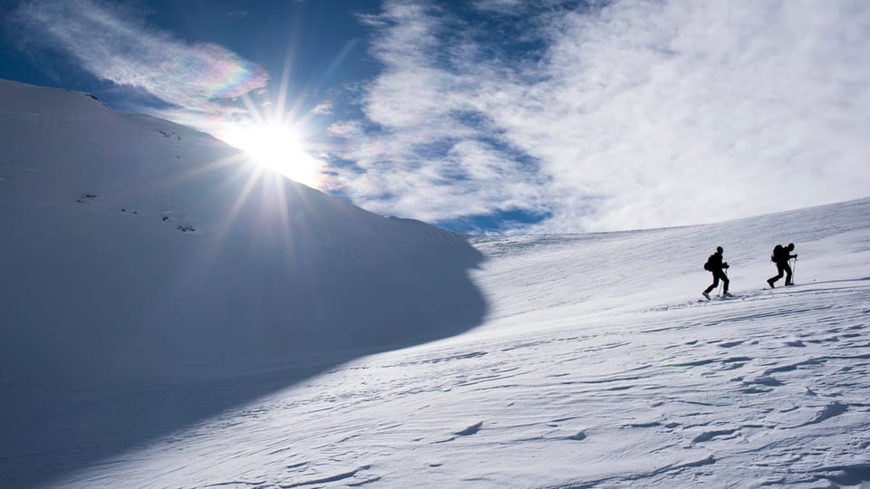 Zwei Skitourengeher im Aufstieg auf einen Berg. 