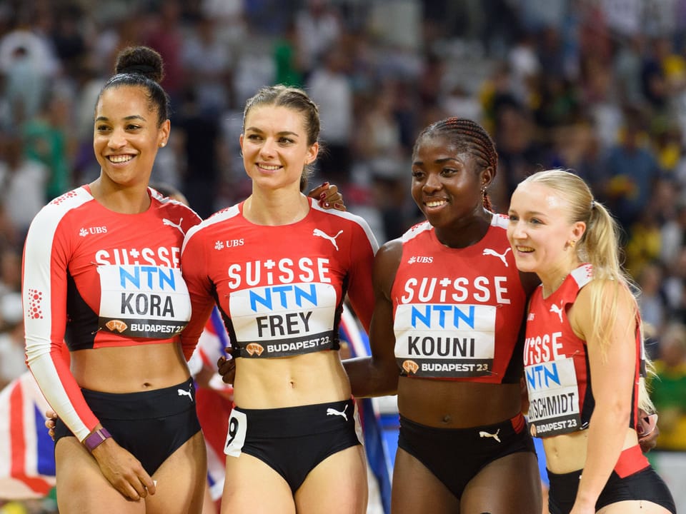 Vier Schweizer Leichtathletinnen in Sportbekleidung lächeln in die Kamera.
