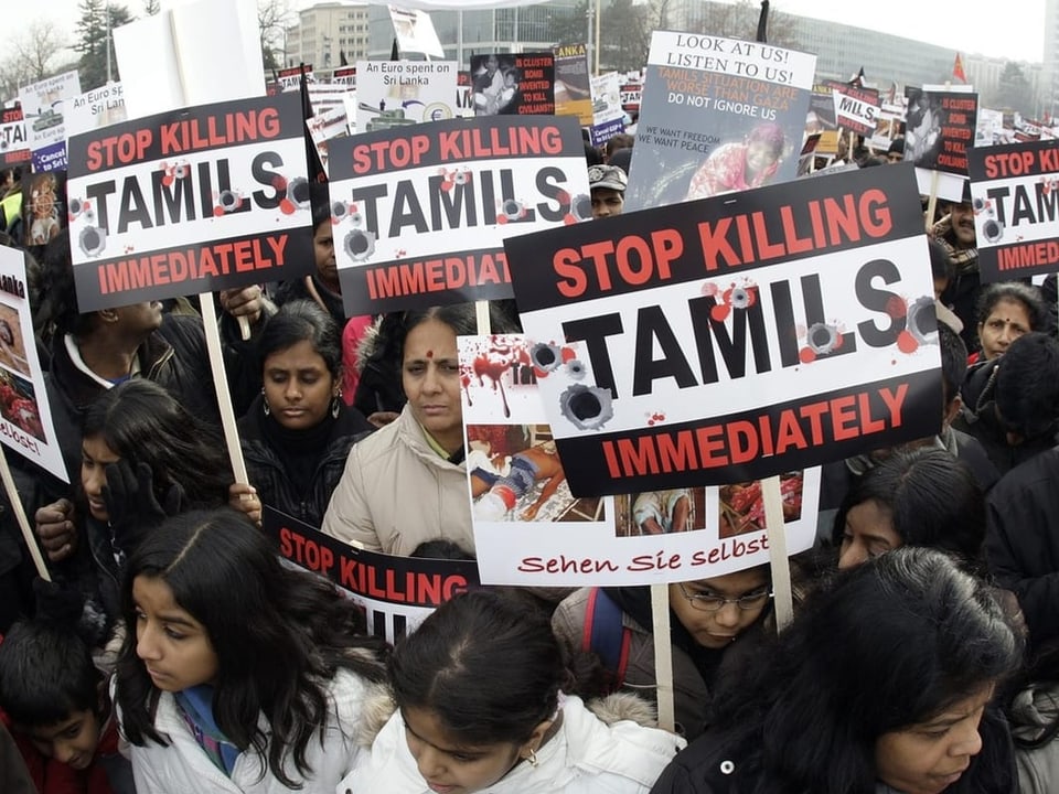 Menschen demonstrieren und halten Plakate mit der Aufschrift «Stop Killing Tamils» hoch