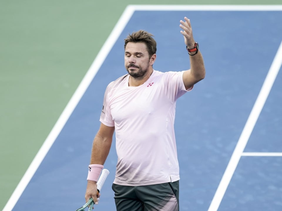 Tennisspieler hebt Hand und schliesst seine Augen auf dem Spielfeld.