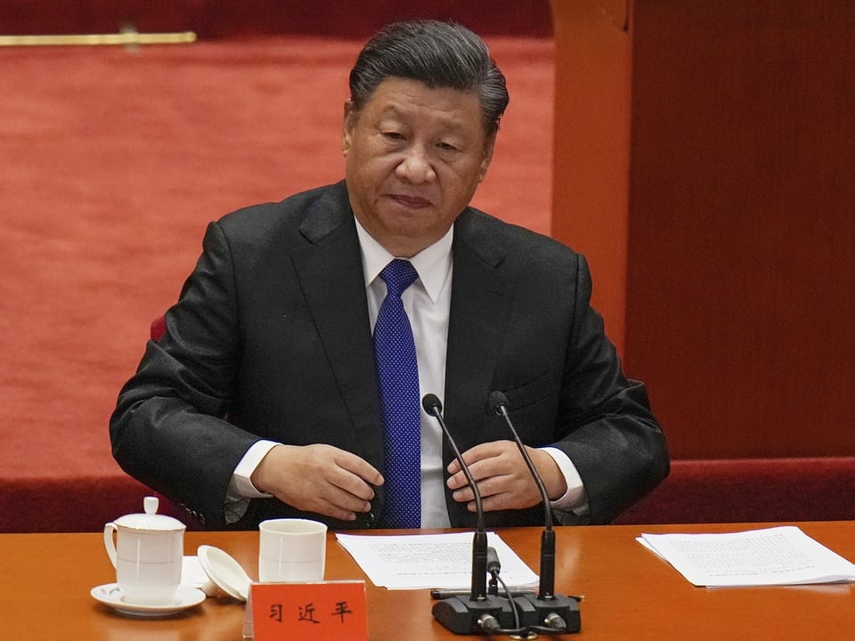 Der chinesische Präsidenten Xi Jinping sitzt an einem Tisch mit Mikrofonen.