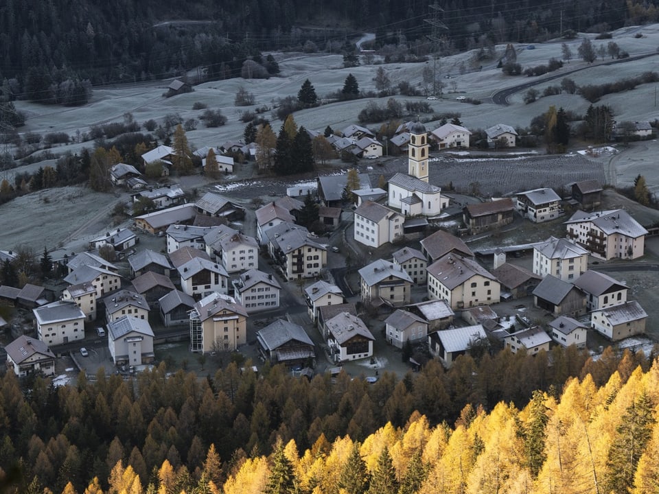 Luftaufnahme eines Dorfes in herbstlicher Landschaft.