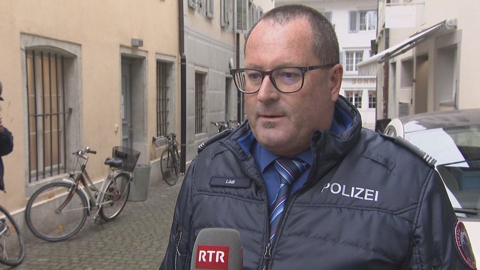 Polizist gibt Interview auf gepflasterter Strasse, Mikrofon von RTR.