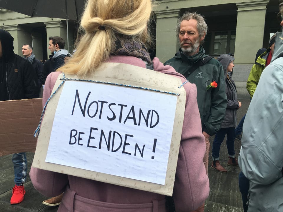 Frau mit Plakat "Notstand beenden"