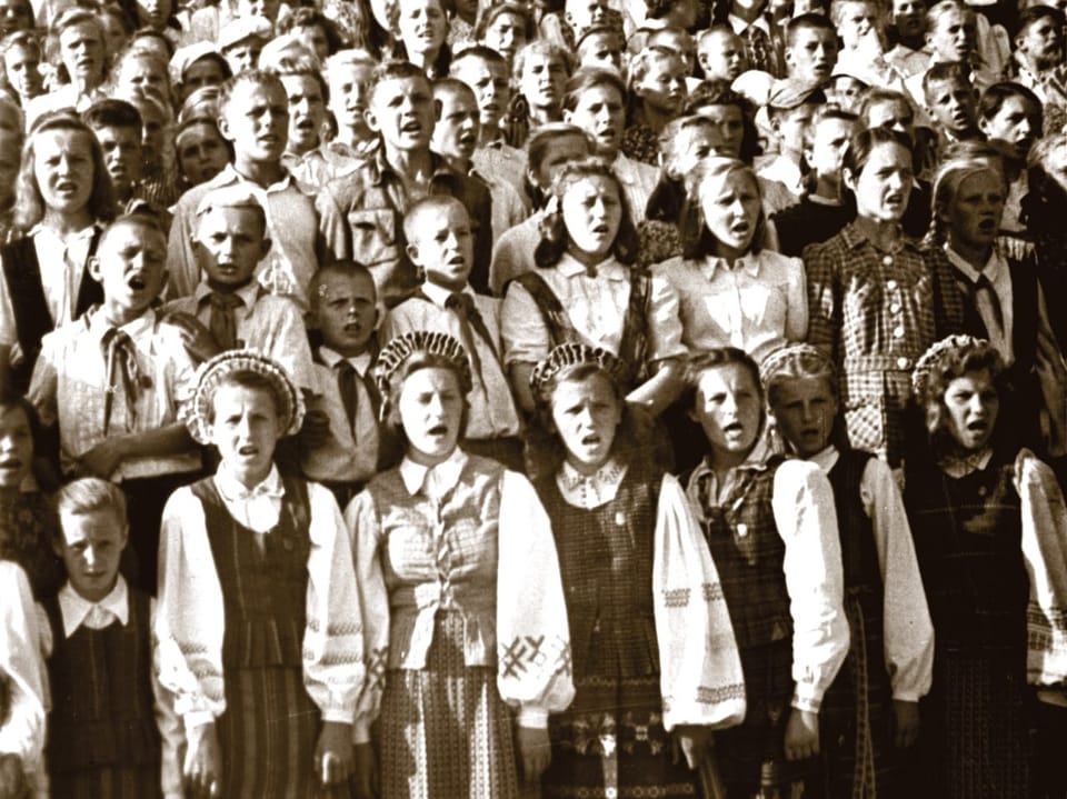 Gruppe von Kindern in traditioneller Kleidung, die zusammen singen.