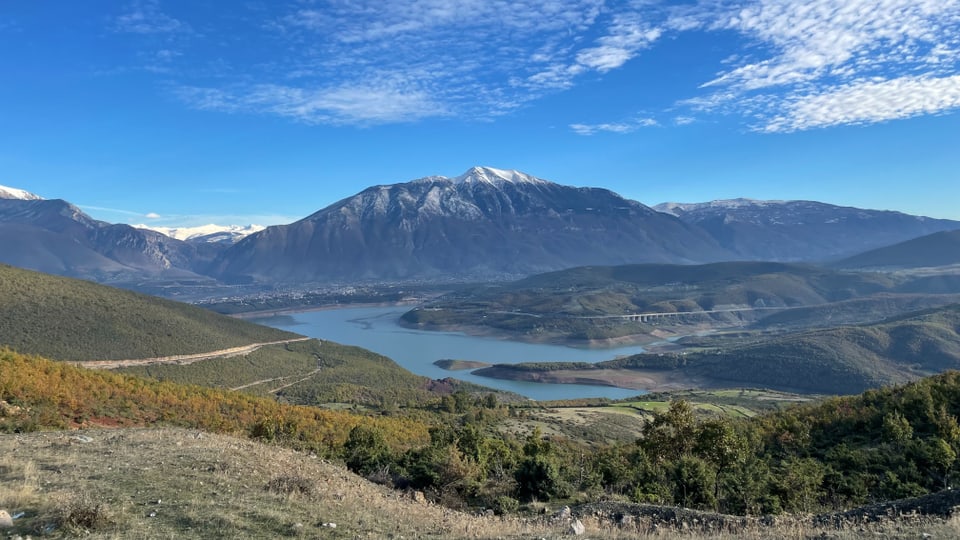 Eine bergige Landschaft mit einem breiten Fluss und einer Stadt in der Ferne