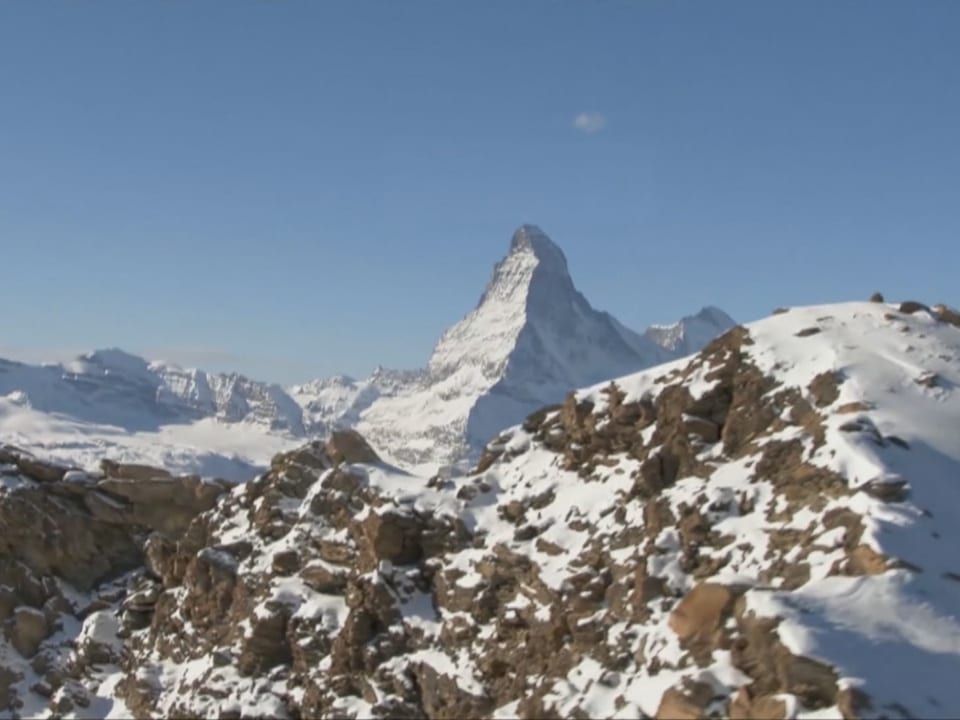 Schneebedecktes Matterhorn vor blauem Himmel.