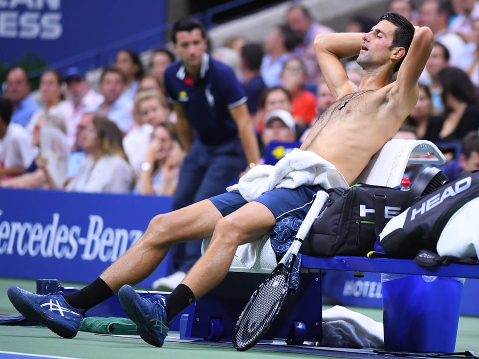 Novak Djokovic sitzt erschöpft auf einem Stuhl.