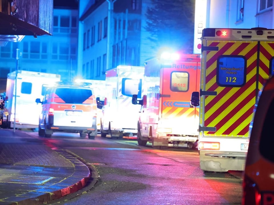 Mehrere Krankenwagen in einer beleuchteten Strasse bei Nacht.