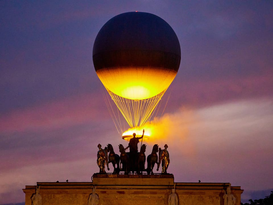Heissluftballon über einem historischen Denkmal bei Sonnenuntergang.