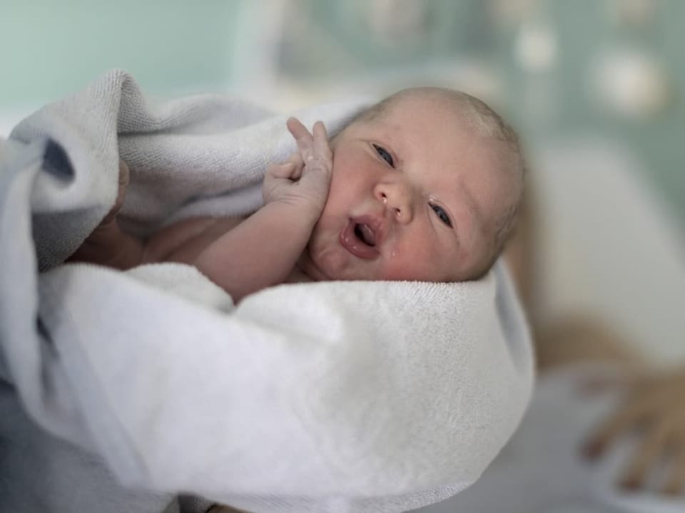 Neugeborenes Baby in einem weissen Tuch