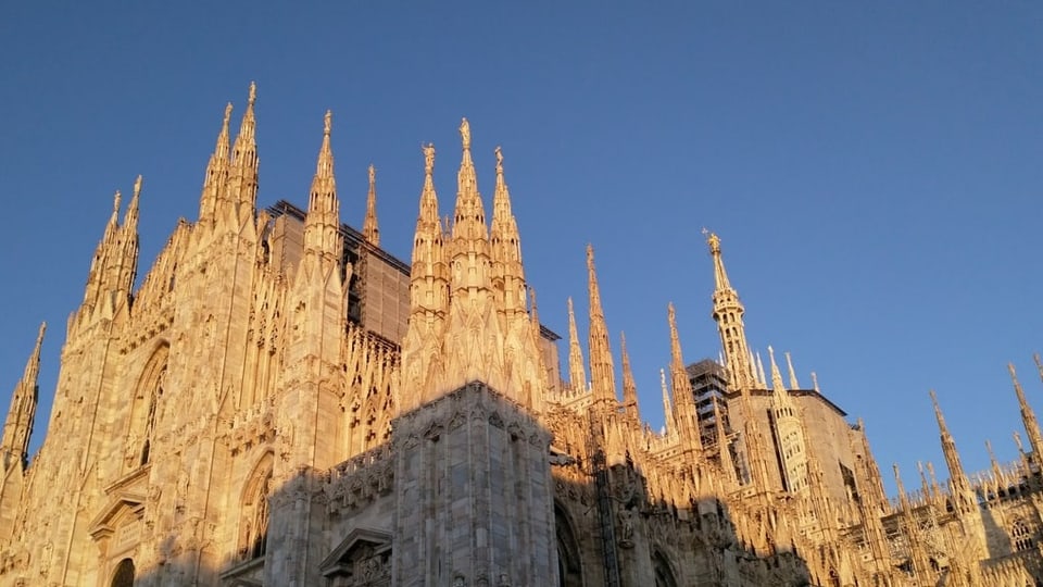 Die feinteiligen Türme des riesigen gotischen DOms strecken sich in die Sonne bei blauem Himmel.