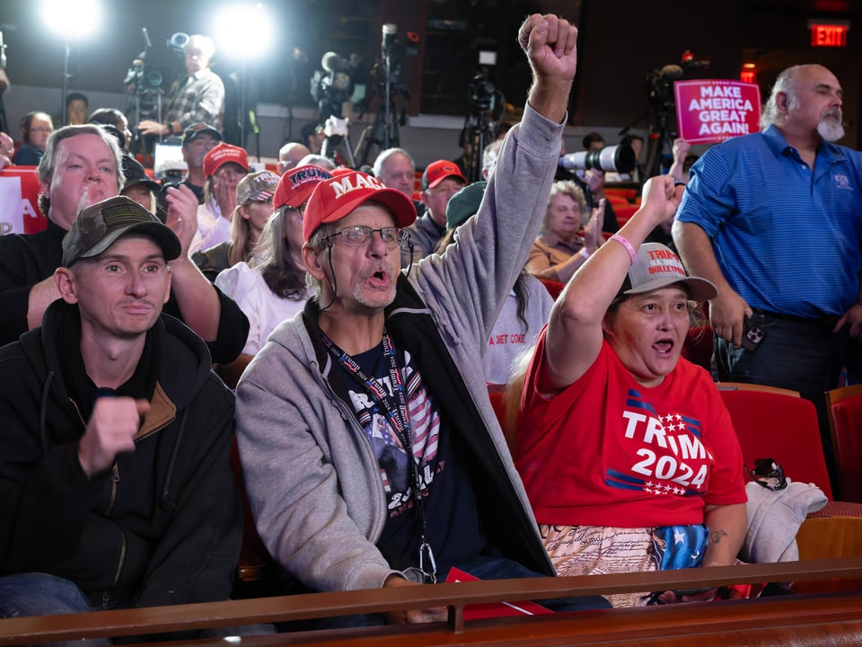 Menschen in Trump-Mützen bei einer Veranstaltung.