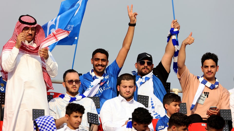 Mehrere Männer auf einer Tribüne in blauen Fan-Utensilien von Al-Hilal