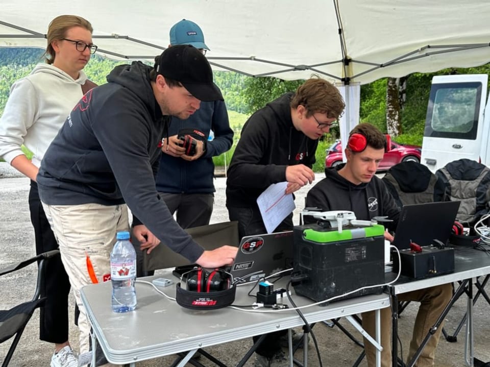 Gruppe von Personen unter einem Zelt, die an Laptops arbeiten.