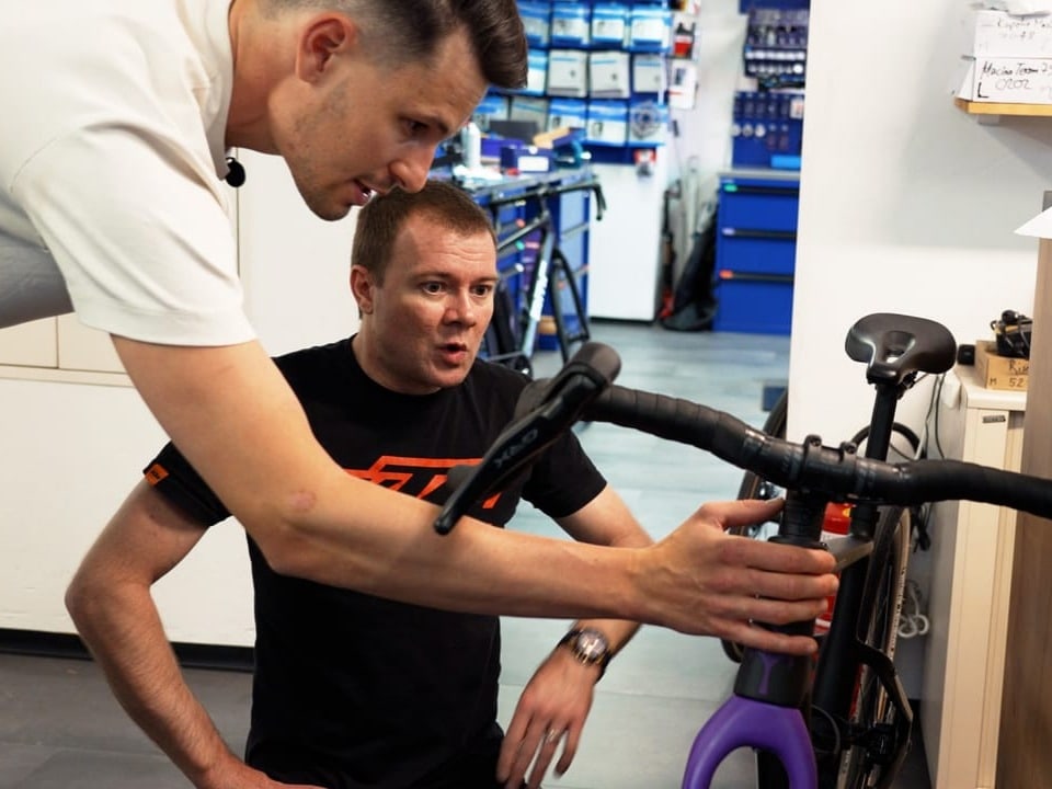 Livio und ein Mitarbeiter besprechen ein Fahrrad zusammen. 