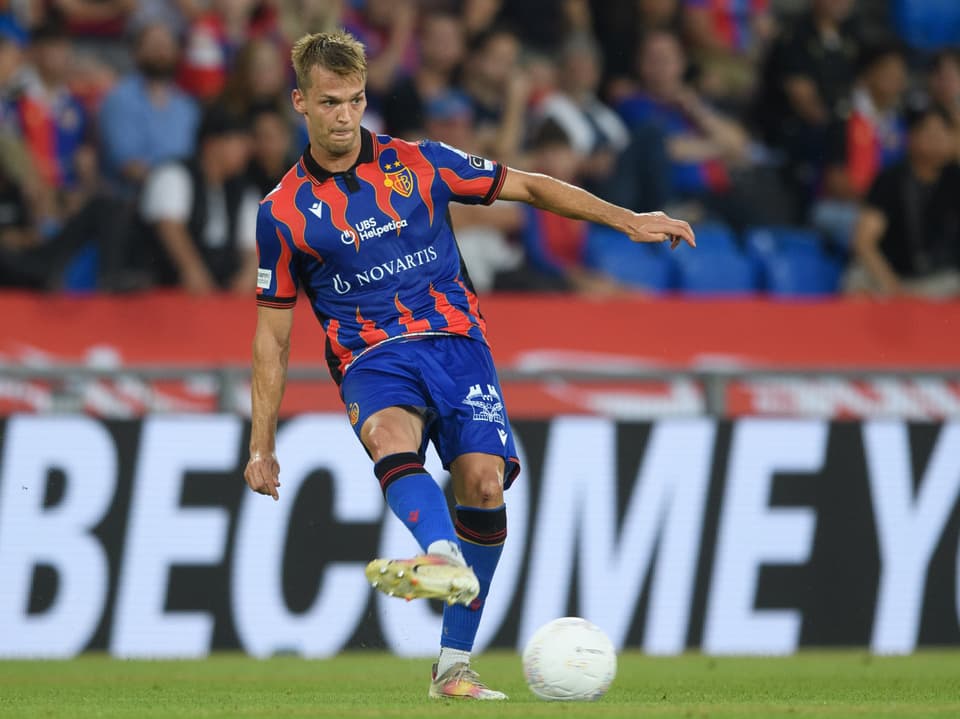 Fussballspieler in blau-rotem Trikot spielt den Ball.