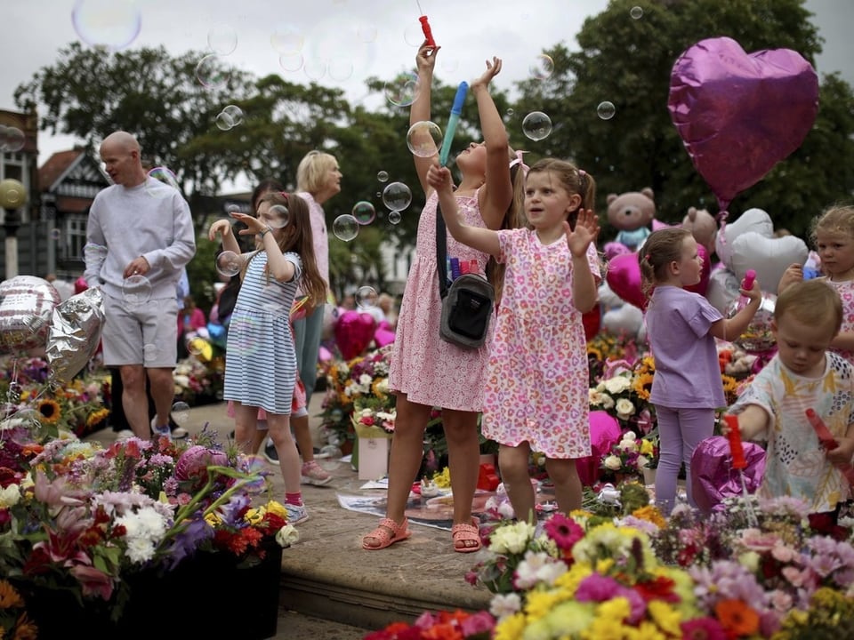 Kinder spielen inmitten von Blumen mit Seifenblasen.