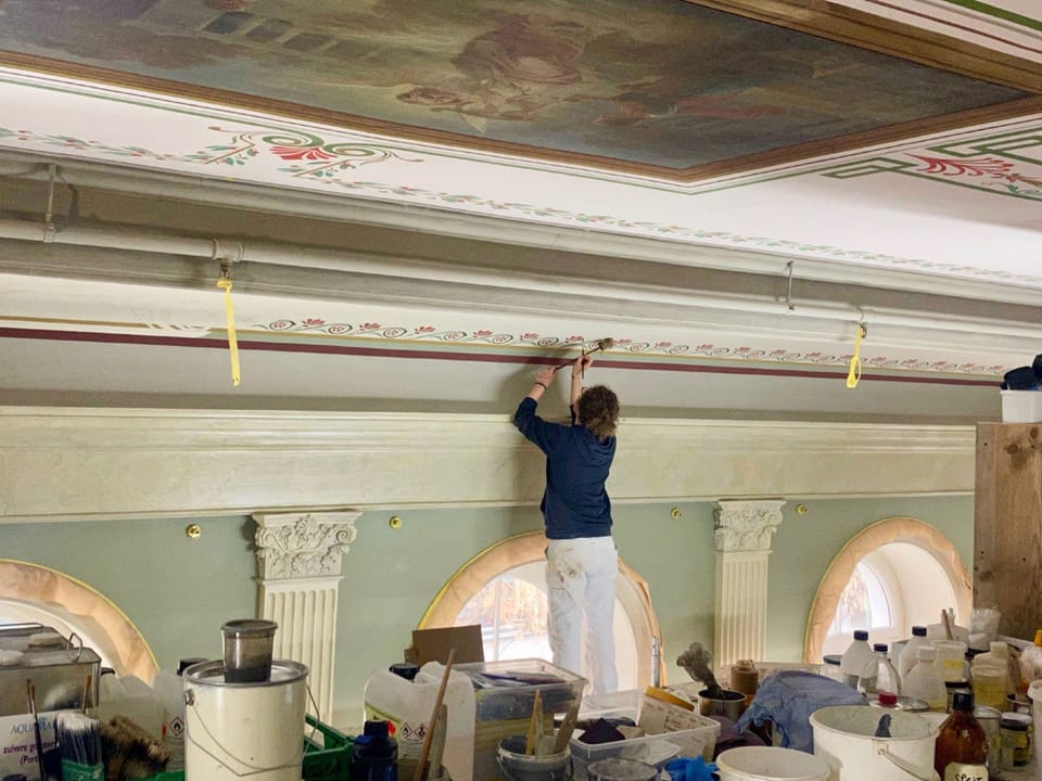 Eine Frau restauriert Ornamente an der Wand