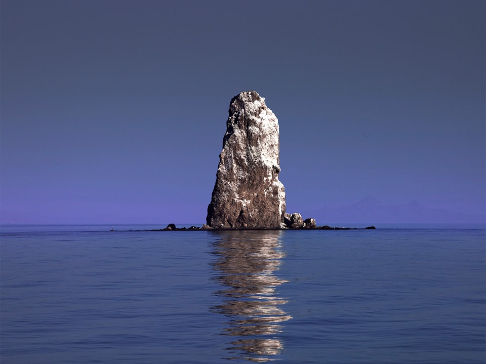 Hoher Fels ragt aus dem blauen Meer.