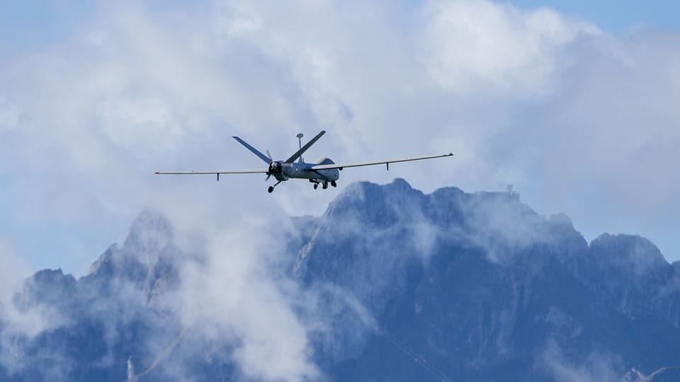 Drohne fliegt vor bergigem Hintergrund in Wolken.