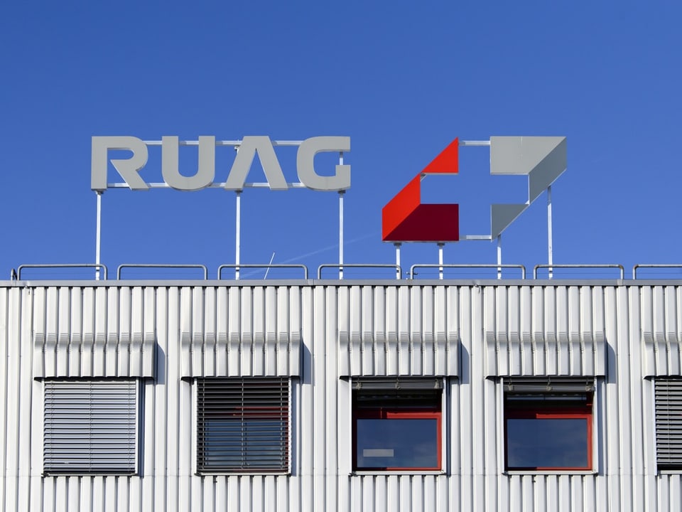 RUAG-Logo auf Gebäudedach vor blauem Himmel.