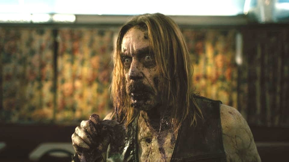 Ein Zombie mit langen Haaren starrt gedankenlos in die Ferne.