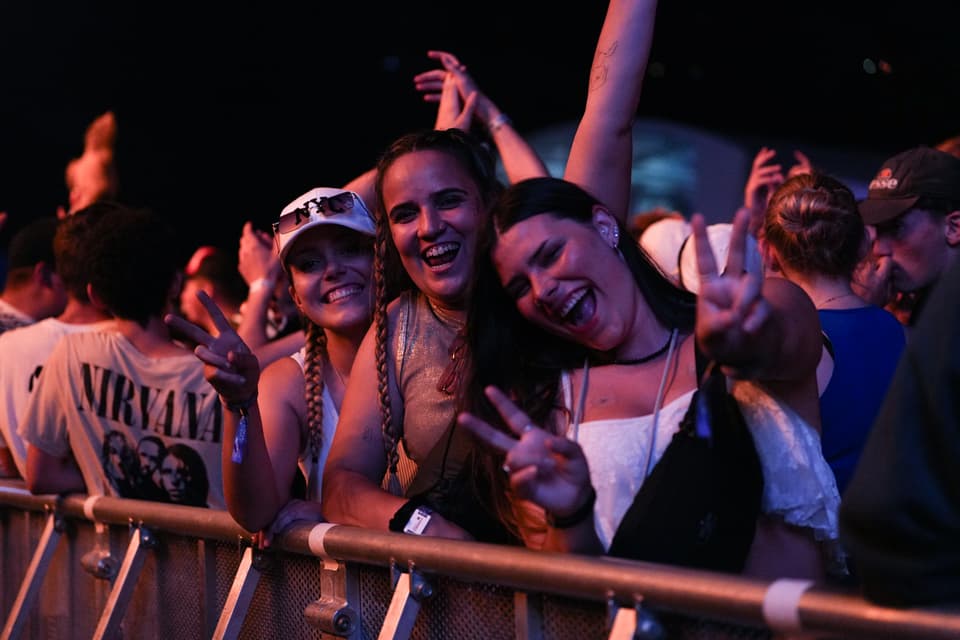 Drei Personen posieren und lächeln bei einem Konzert.