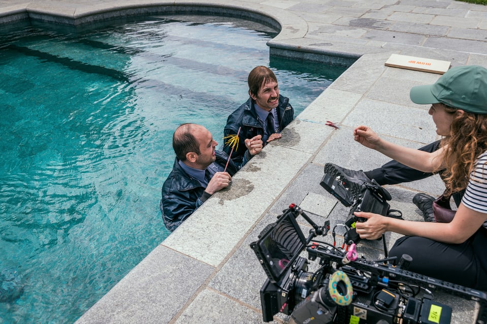 Szenendreh: Bax und Pirmin stehen in einem Pool und reden mit der Kamerafrau rechts von ihnen am Rand des Pools.