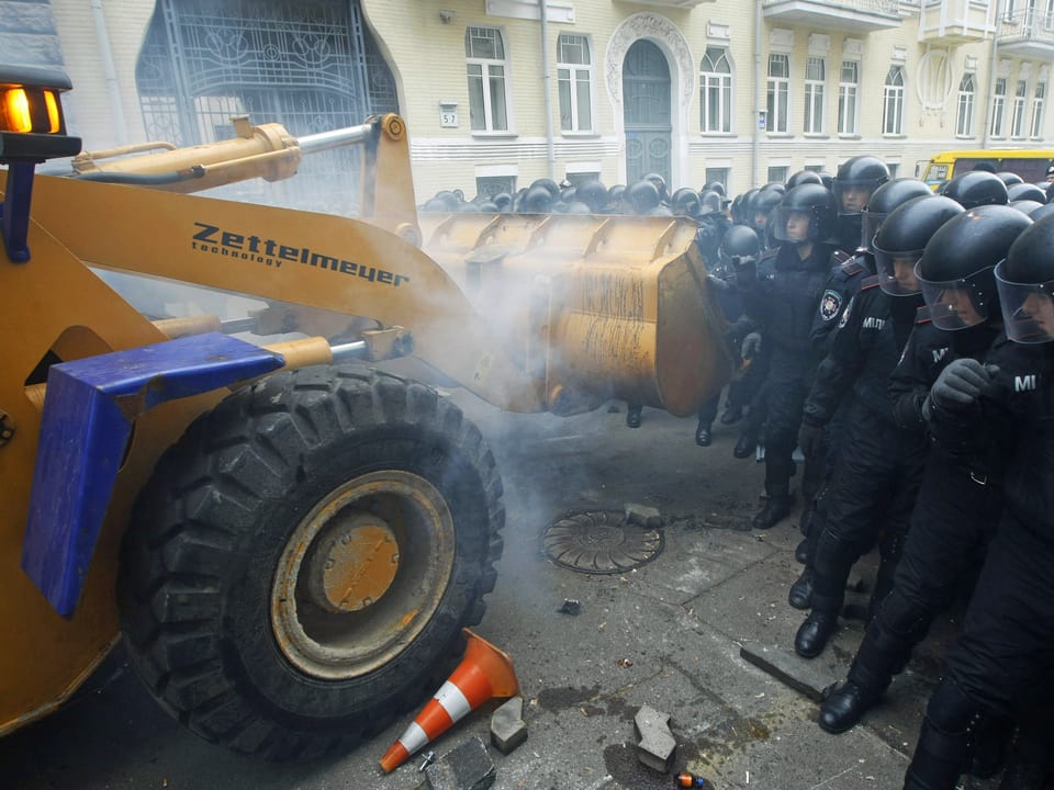 Bagger fährt auf Polizisten zu.